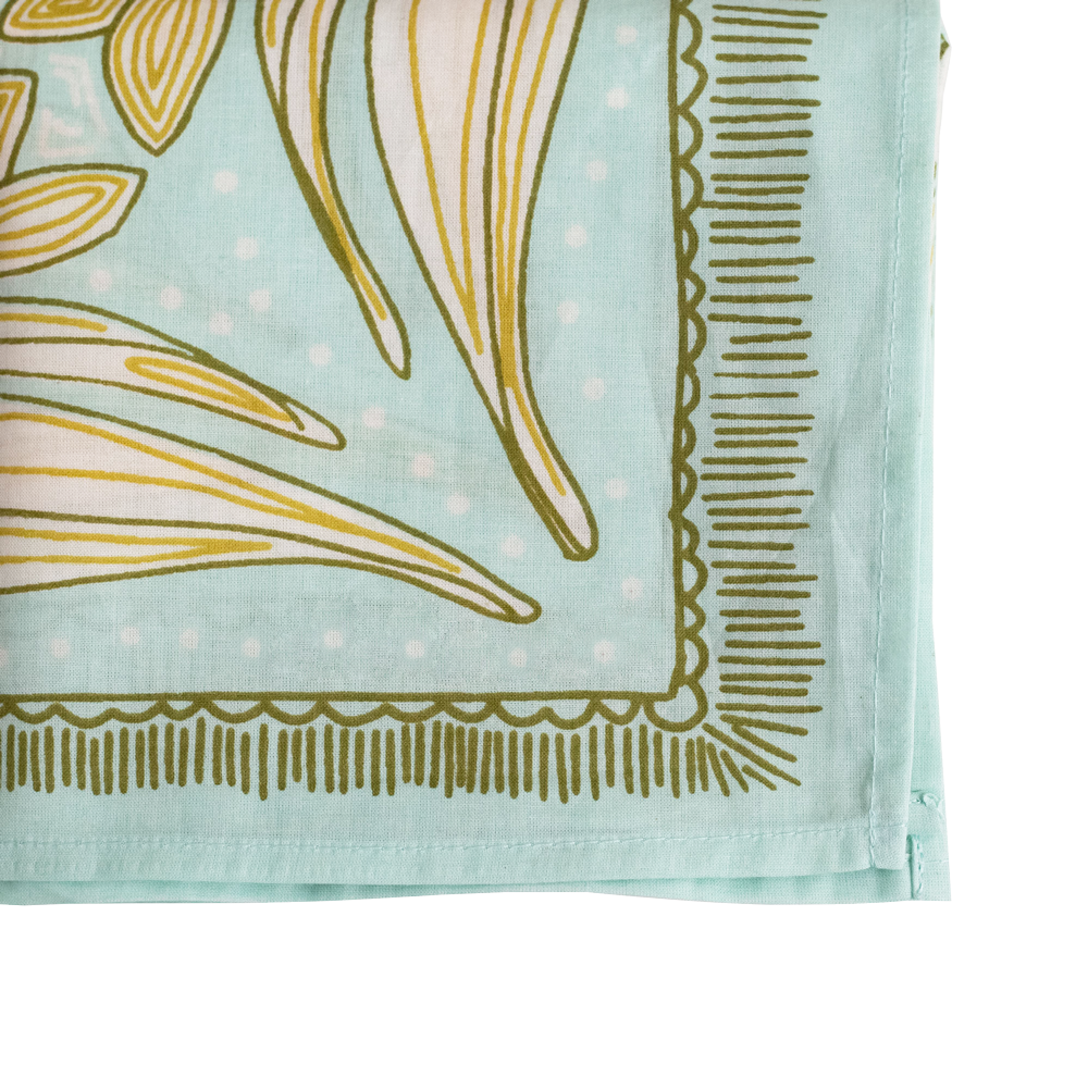 A close-up of the Handker Bandanas No. 012 Eliza Bandana by Handker Bandanas, featuring premium cotton in light blue with white dots, yellow and olive green abstract florals, and a decorative green border.