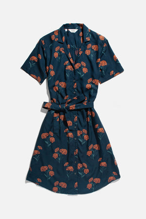 The Sofia Shirt Dress / Wildflower by Bridge & Burn is a navy blue, short-sleeved, knee-length modal dress with a collar, button front, self-belt, and orange floral pattern—ideal for sustainable summer style.