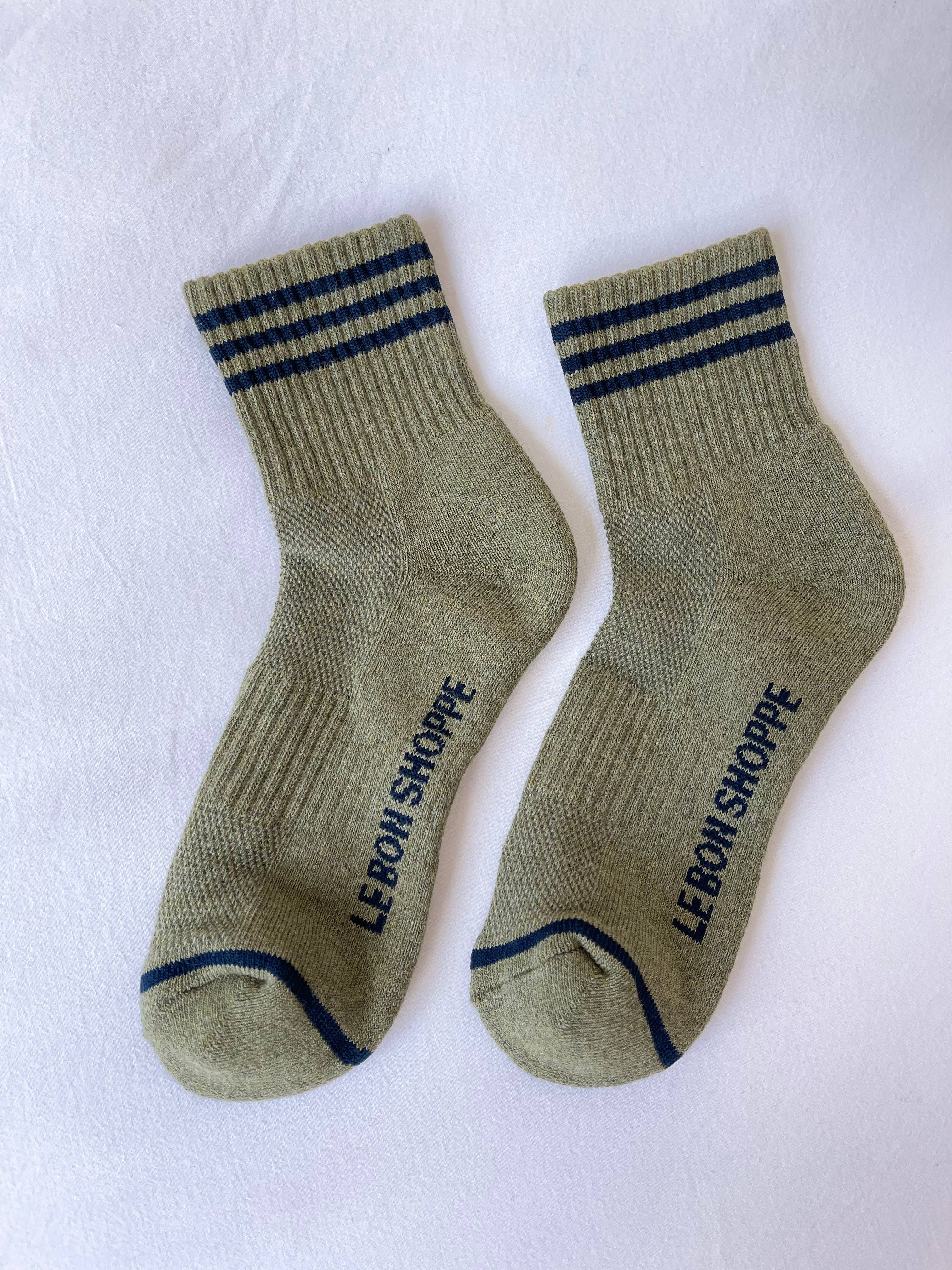 Le Bon Shoppe - Girlfriend Socks in Sage: Light olive green crew socks with dark blue top stripes and “LE BON SHOPPE” printed in blue on the soles, shown on a white background.