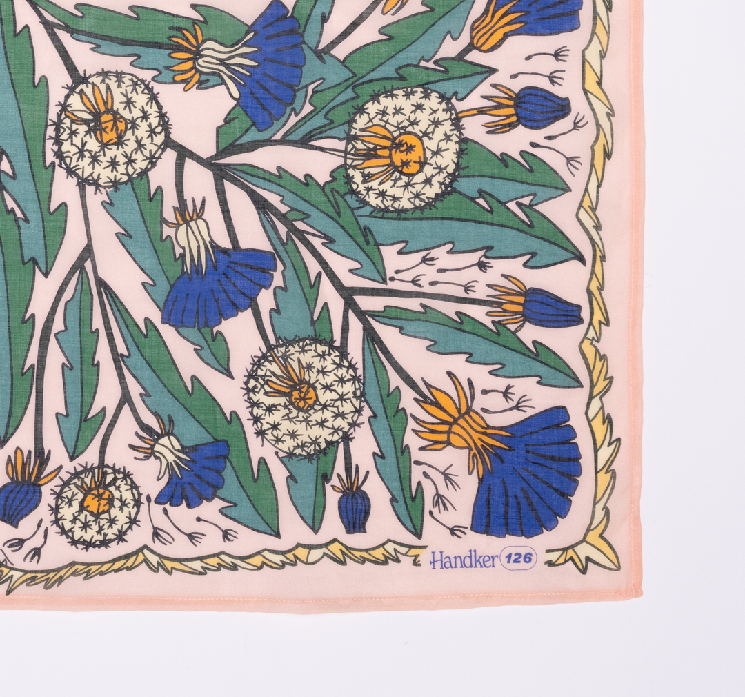 The Handker Bandanas - 34" Dandy Wild Rag Bandana is crafted from cotton lawn, hand screen-printed with green leaves, dandelion flowers, and blue blooms. It features a peach border framing "Handker 126" in the bottom right corner.
