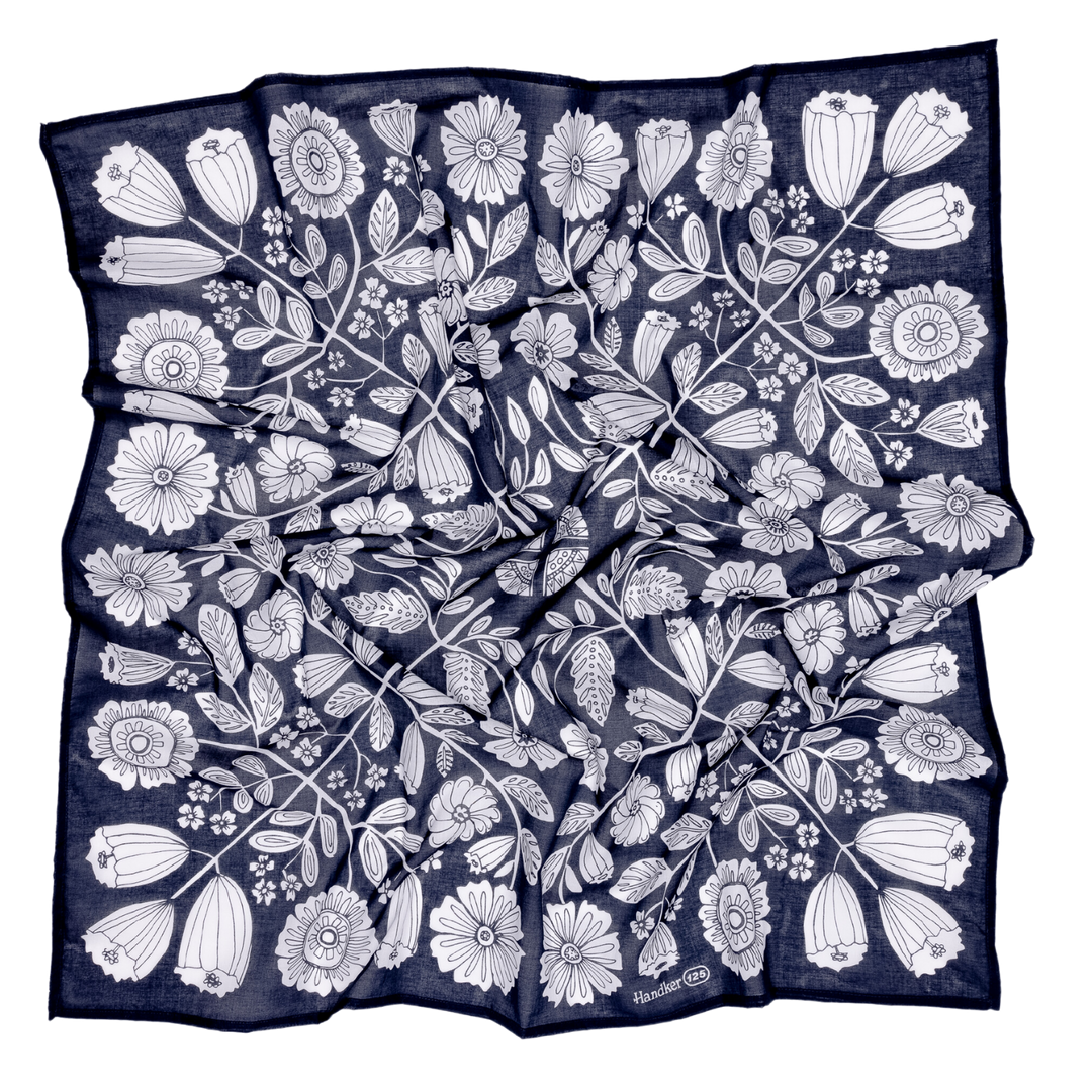 The Handker Bandanas 34" Wild Rag Fiona Bandana is a large navy cotton lawn scarf with a white floral pattern. Hand screen-printed for a slightly wrinkled look, it features stylized flowers and leaves in a nature-inspired design.