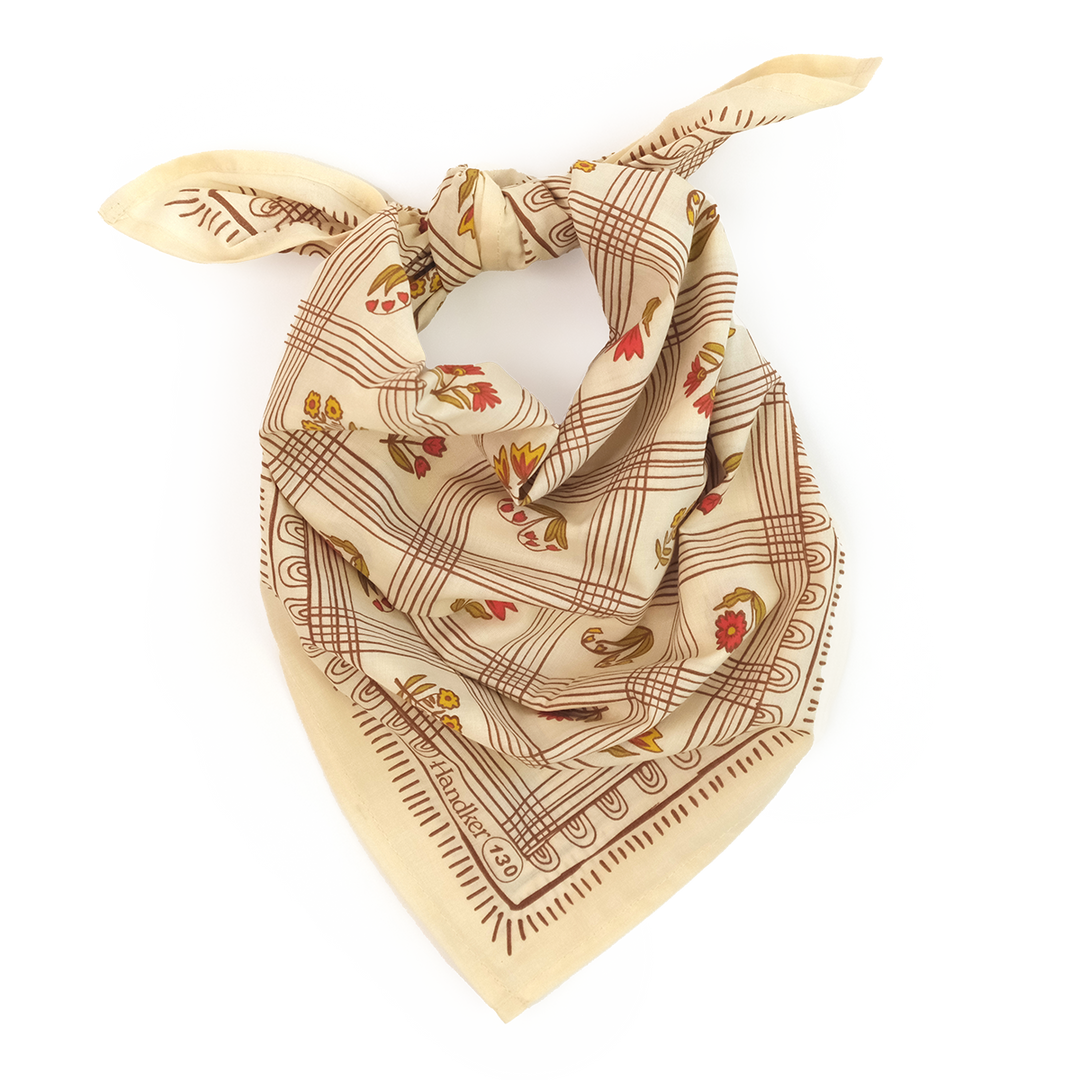 The Handker Bandanas No. 130 Laura Bandana by Handker Bandanas is a premium cotton bandana with a brown checkered pattern and red, yellow, and brown floral designs, hand screen-printed and shown loosely knotted on a white background.