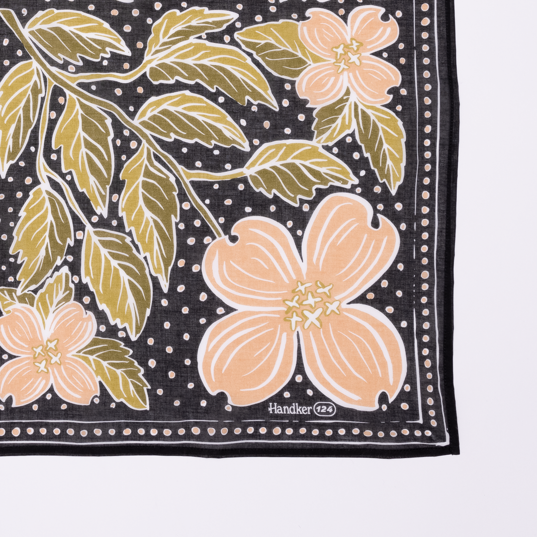 The Handker Bandanas - 34" Wild Rag Amy Bandana by Handker Bandanas features a black background, peach and green floral design, white dotted accents, a thin white border, and "Handker" with "24" in one corner. A stylish cotton bandana accessory.