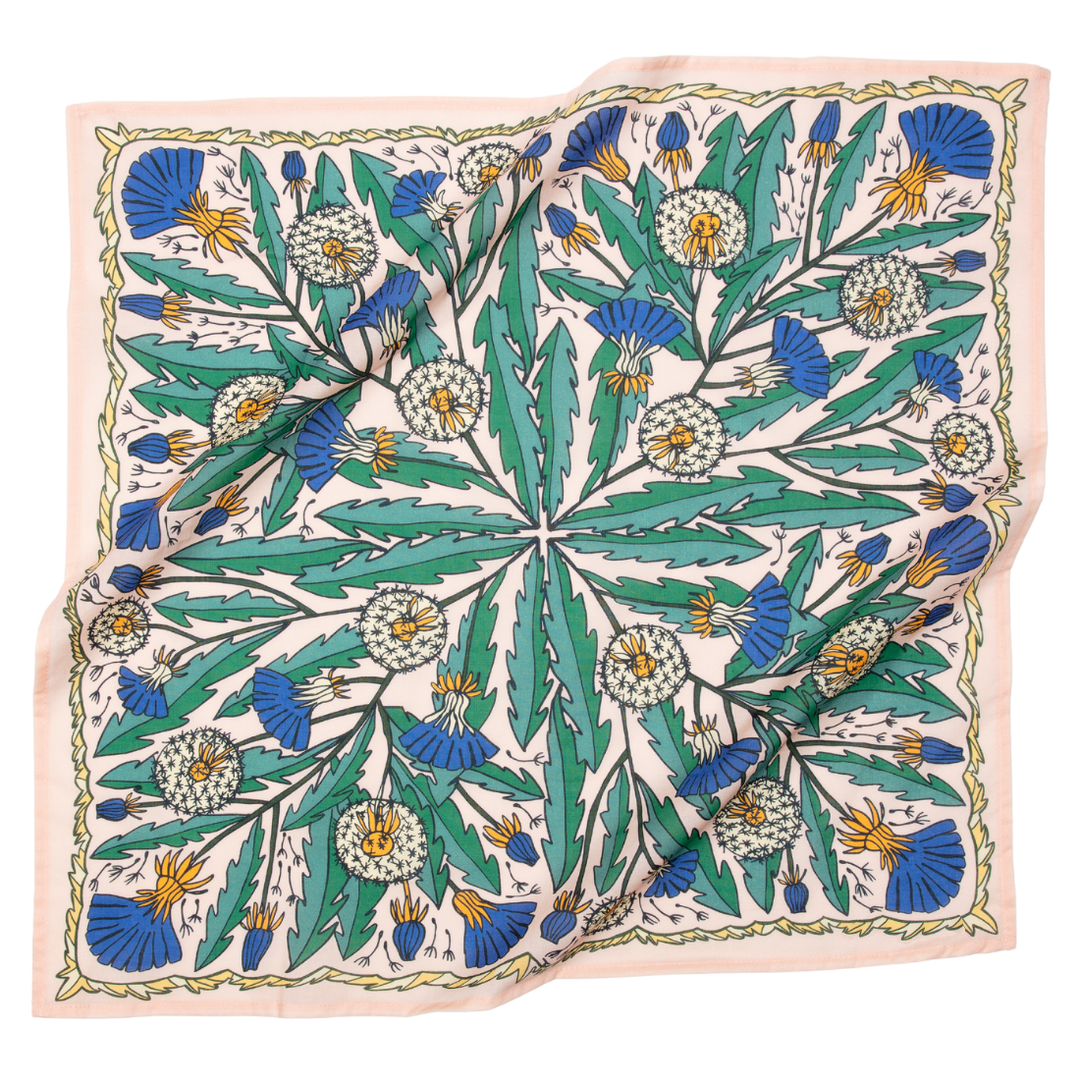 The Handker Bandanas - No. 103 Dandy Bandana features a square, premium cotton fabric with a colorful botanical pattern of green leaves, blue and yellow flowers, and white dandelion puffs on a light background. Slightly wrinkled finish.