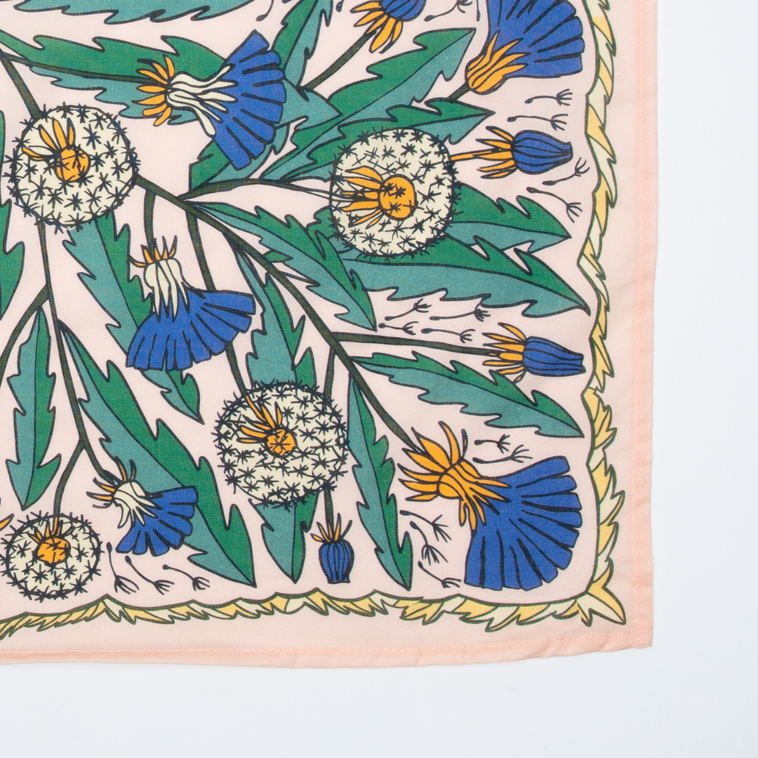 The Handker Bandanas - No. 103 Dandy Bandana by Handker Bandanas is a premium cotton square scarf featuring green leaves, dandelion seed heads, and blue and yellow flowers on a pale background with a peach border.