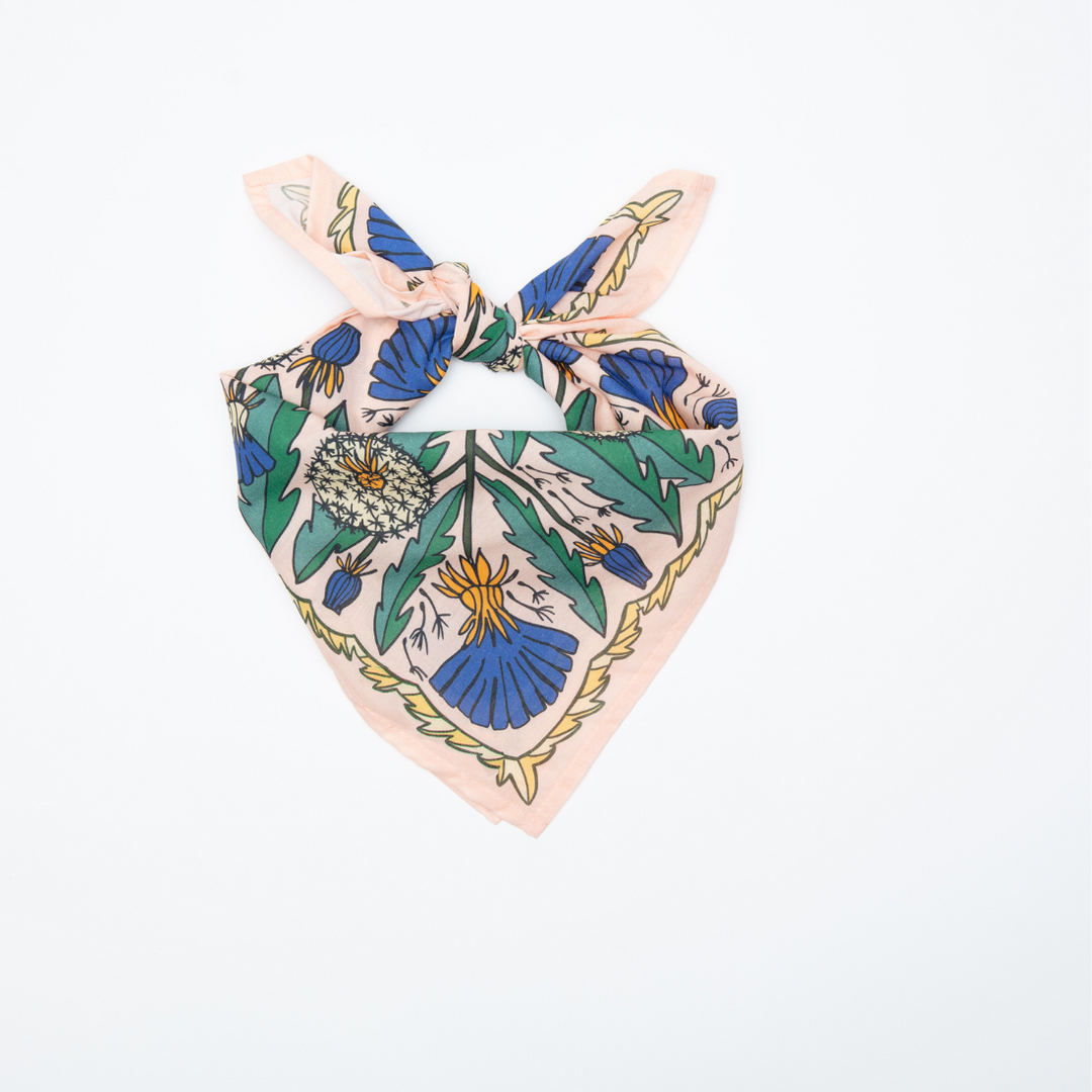 The Handker Bandanas - No. 103 Dandy Bandana by Handker Bandanas is a square accessory with a beige base and blue, green, and yellow floral patterns, displayed knotted at the top on a plain white background.