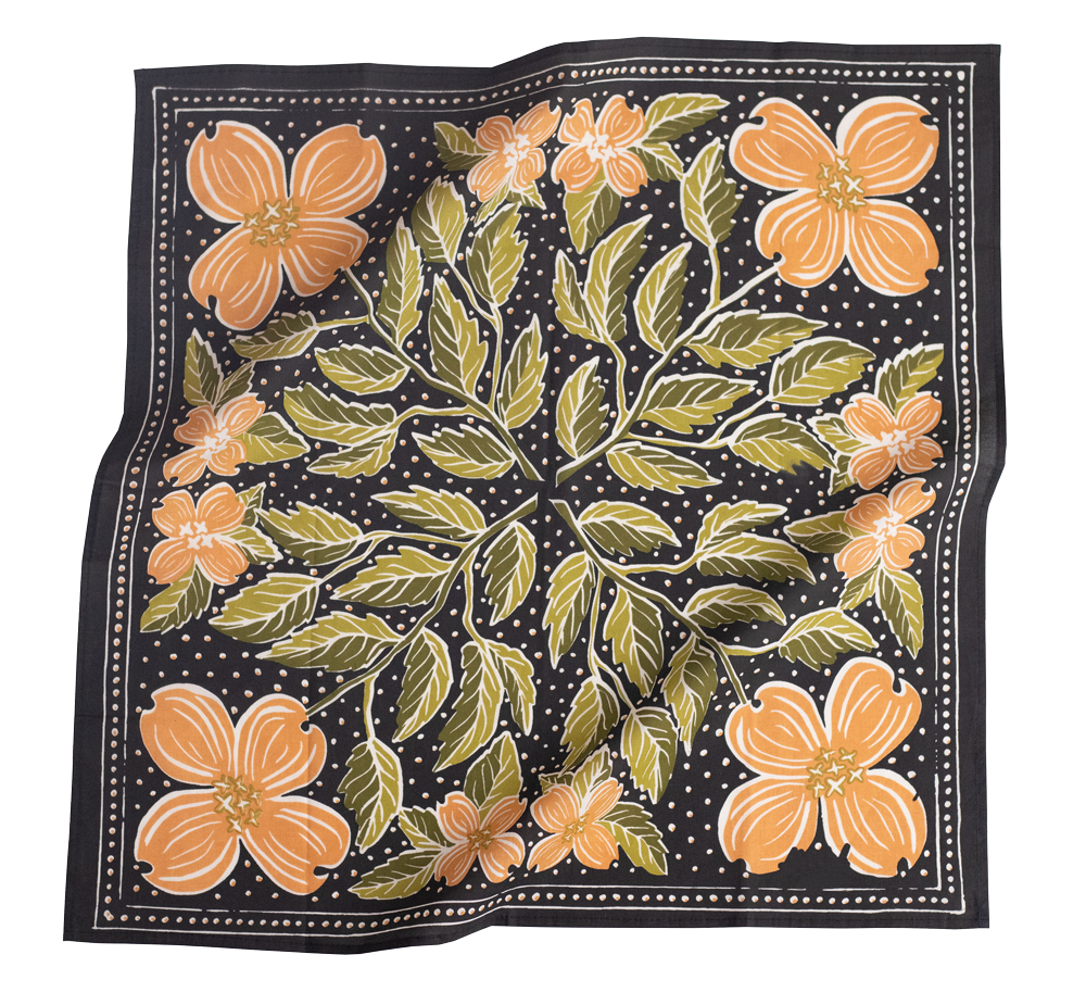 The Handker Bandanas - No. 046 Amy Bandana by Handker Bandanas is a square cotton bandana with large orange dogwood flowers, green leaves, and small white dots on a black background. Fabric has a slightly wrinkled look.