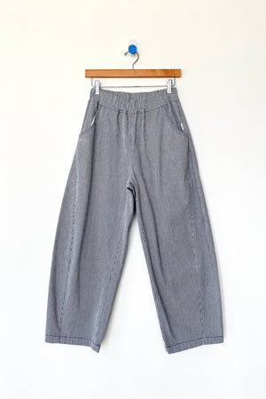 Le Bon Shoppe - Arc Pant in Blue Stripe features a wide-leg silhouette with an elastic waistband and convenient side pockets, crafted from heavyweight canvas for lasting durability. Displayed on a wooden hanger against a clean white background, these stylish everyday pants by Le Bon Shoppe are perfect for elevated comfort and style.