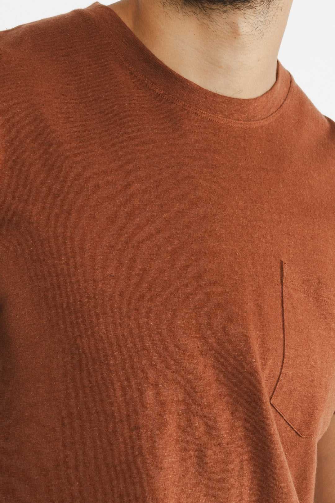 Close-up of the Bridge & Burn Organic Hemp Pocket Tee in Burnt Umber. The image highlights the textured fabric, chest pocket, and neckline; the wearer’s face is not visible.