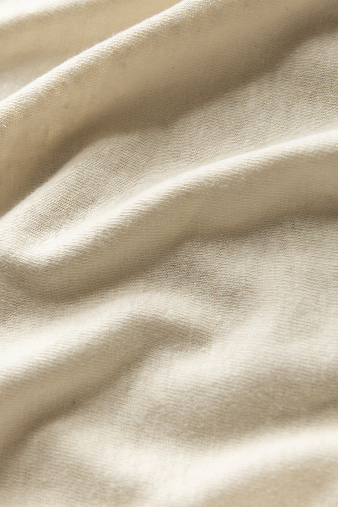 Close-up of the ivory Organic Hemp Pocket Tee by Bridge & Burn, showing its light beige fabric with soft folds and subtle texture—highlighting the smooth comfort and sustainability perfect for any eco-friendly tee collection.