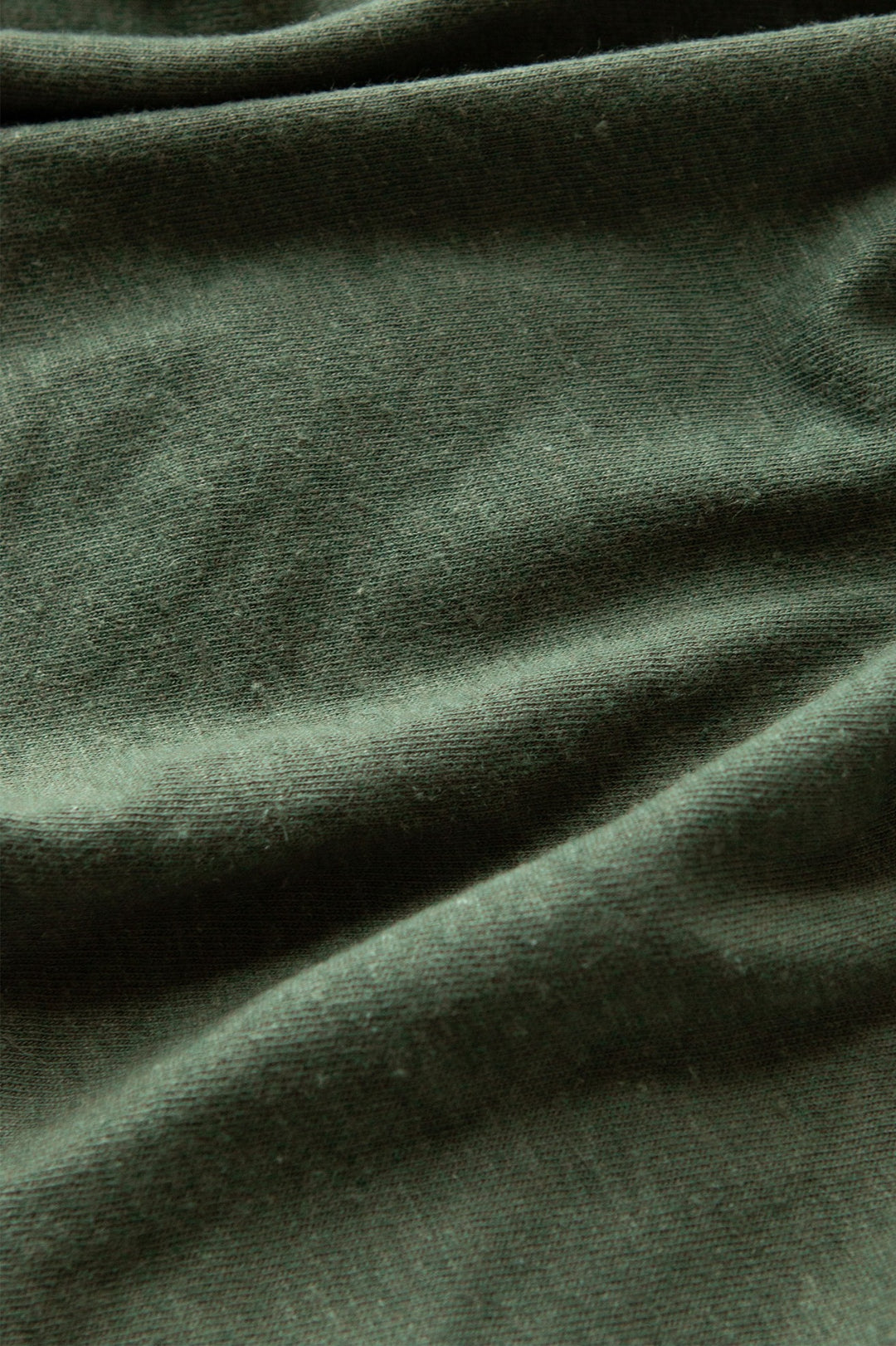 Close-up of the Bridge & Burn Organic Hemp Pocket Tee in Cypress, showing its dark green organic cotton-hemp fabric with a soft texture, gentle folds, and subtle shadows—highlighting this sustainable t-shirt’s quality.