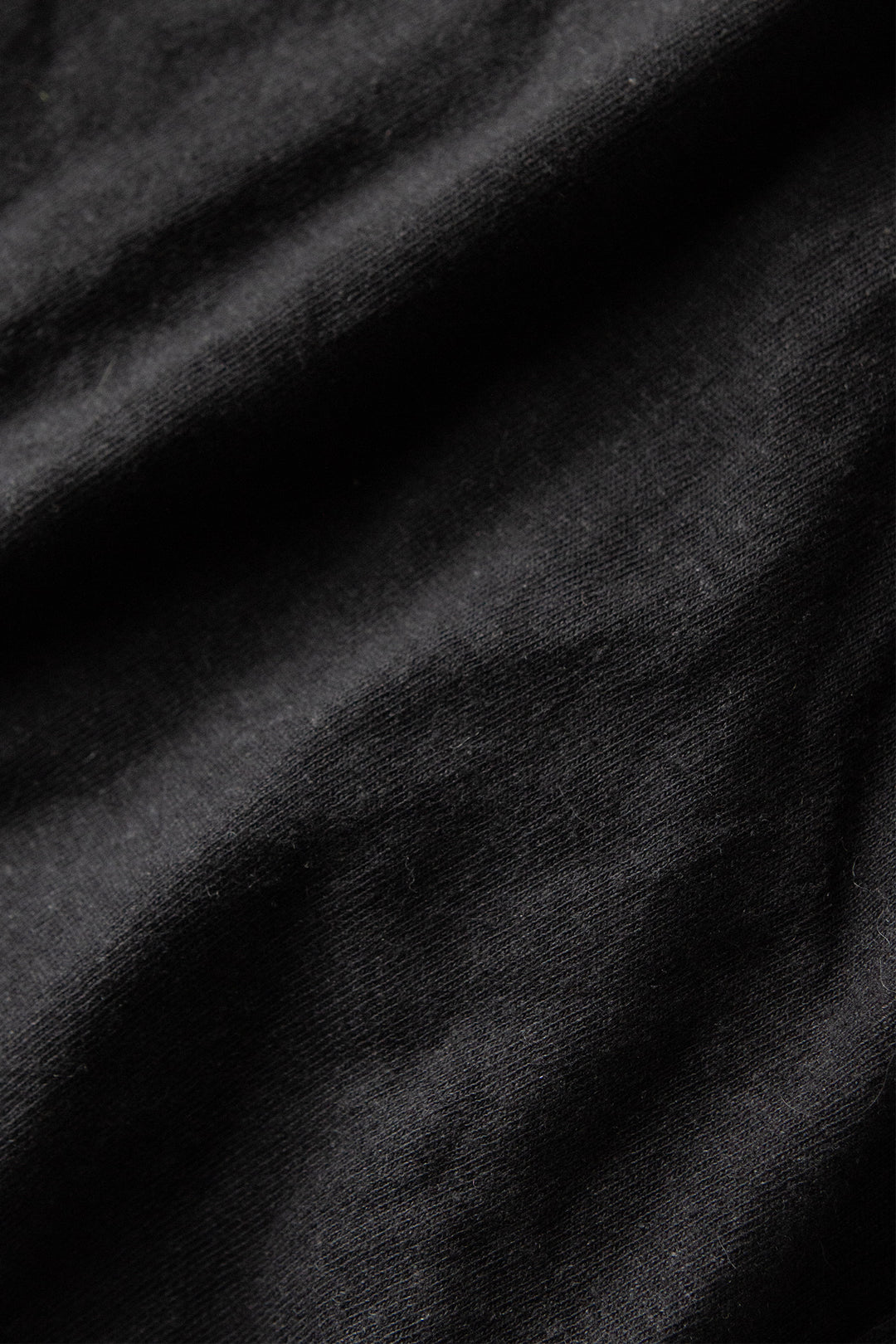 Close-up of Bridge & Burn's Organic Hemp Boxy Tee in Washed Black, highlighting the soft texture and subtle folds of its sustainable midweight jersey fabric.