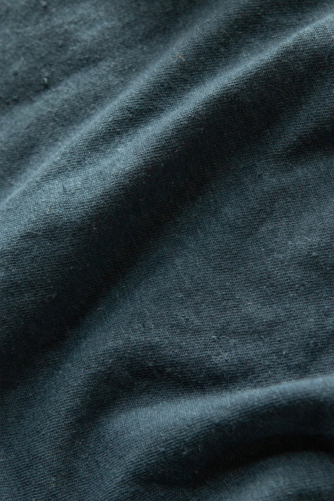 Close-up of Bridge & Burn's Organic Hemp Boxy Tee in Storm Blue, showcasing its dark, textured organic cotton hemp fabric with soft diagonal folds and a vintage-inspired look.