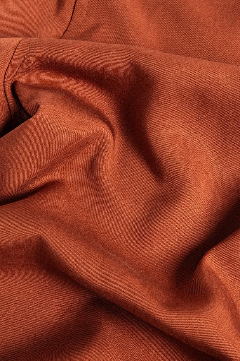 A close-up of the Bridge & Burn Greer Cropped Shirt in Copper, highlighting its soft Tencel fabric, visible seams, smooth texture, and gentle creases that emphasize its boxy fit.