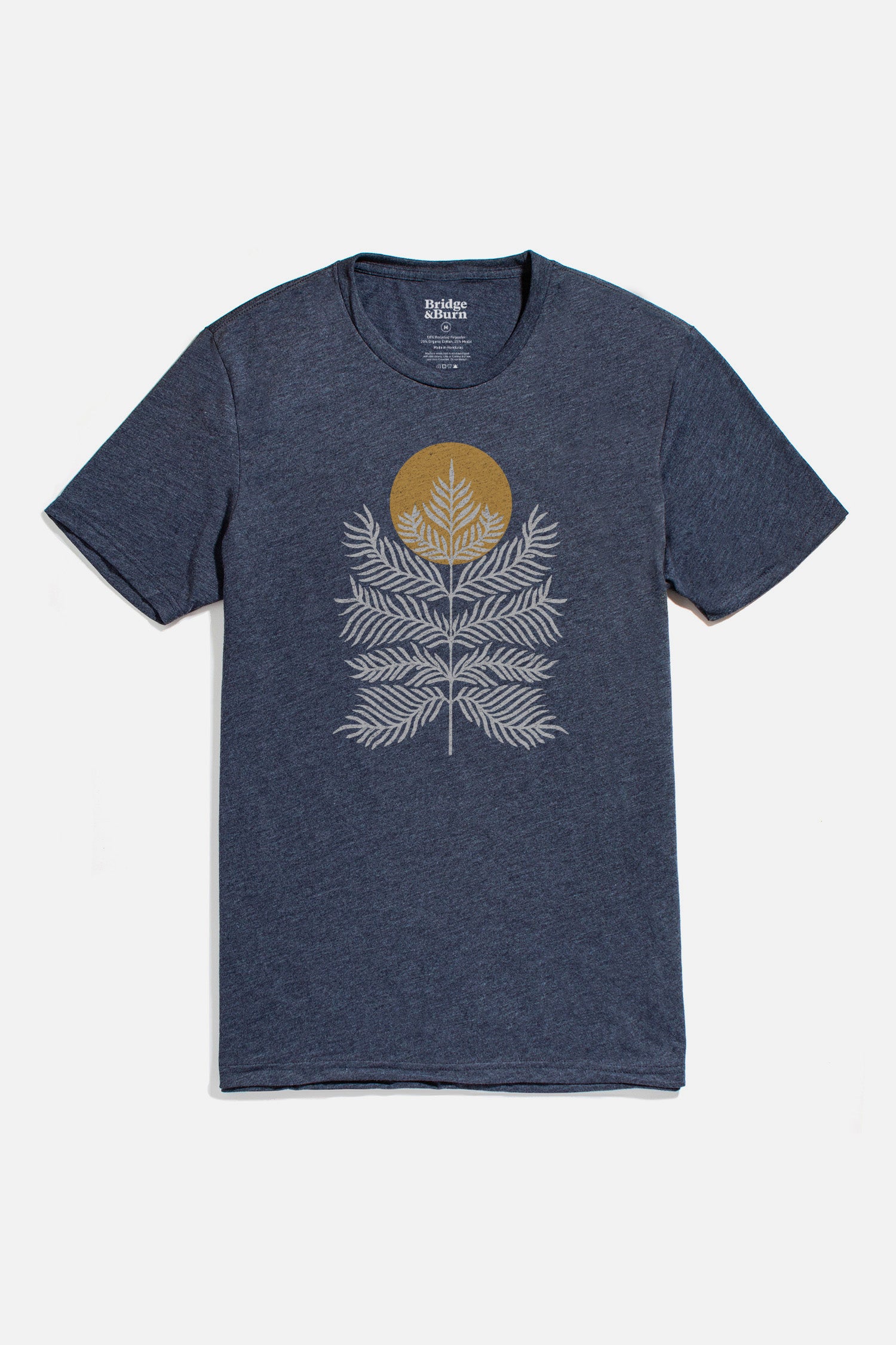 The Bridge & Burn Men's Peace in Plants Tee in navy is a lightweight shirt featuring white layered fern graphics and a gold sun-like circle centered on the chest.
