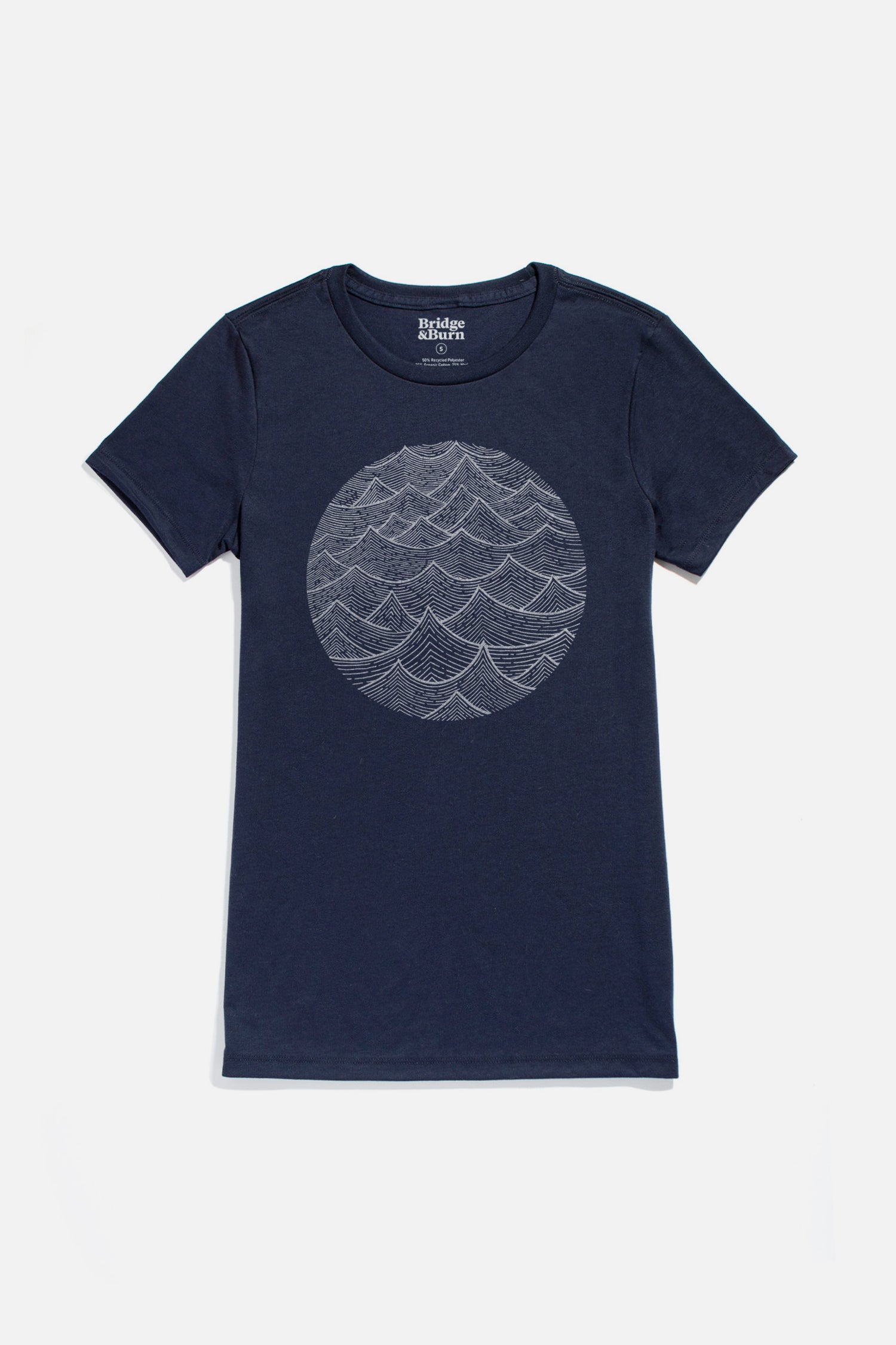 The Women's Waves Tee by Bridge & Burn is a navy blue, short-sleeve organic cotton shirt with a white line art wave design on the chest, displayed flat on a white background.