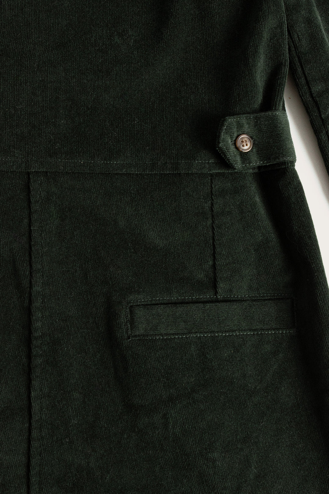 Close-up of the Bridge & Burn Faye Jumpsuit in Deep Pine Pinwale, showcasing a pocket, waistband with buttoned tab, and distinct vertical corduroy ridges.