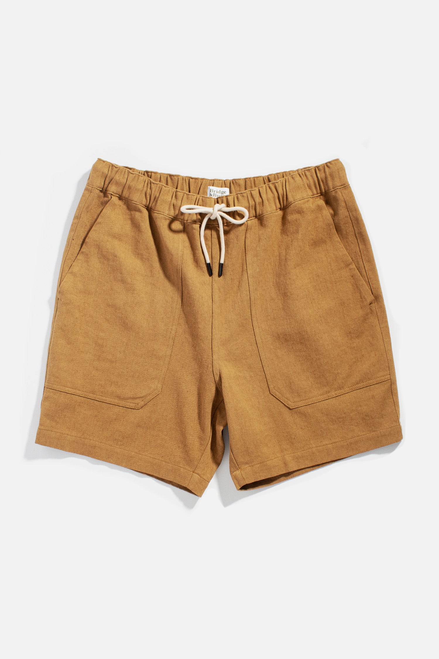 The Noah Short by Bridge & Burn in ochre features a relaxed pull-on style with elastic waistband, white drawstring, and two front pockets, crafted from a linen-cotton blend and shown flat on a white background.
