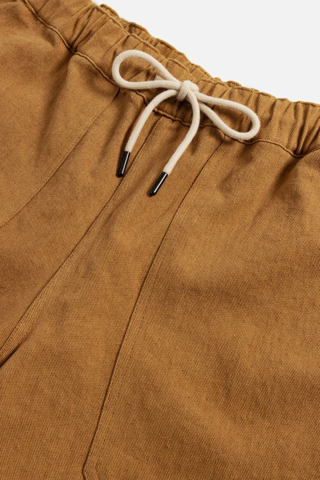 Close-up of the Noah Short in Ochre by Bridge & Burn, featuring a light brown linen-cotton blend, elastic waistband, and a white drawstring with metal tips. The fabric looks soft and textured.