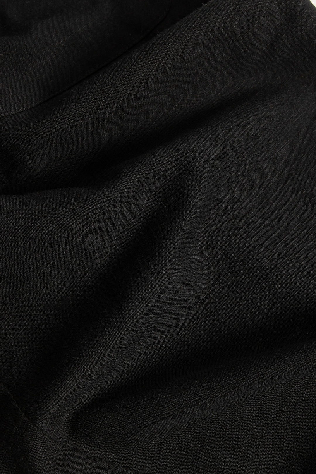 A close-up of the Edie Overall in Black by Bridge & Burn reveals the visible texture and subtle folds of its fine tencel-cotton blend fabric, often chosen for wide-leg overalls with adjustable straps that combine comfort and style.