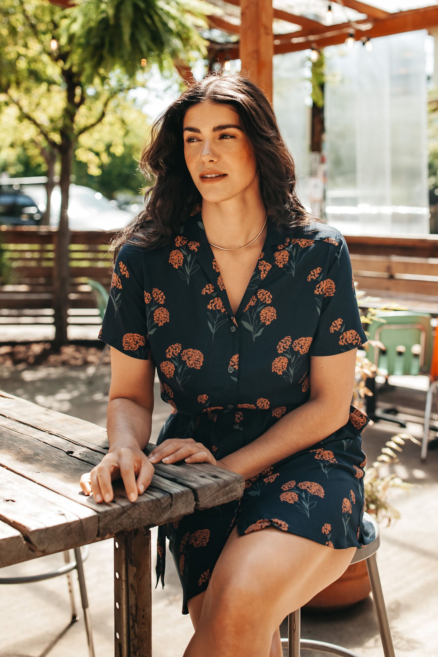 The Sofia Shirt Dress / Wildflower by Bridge & Burn is a navy blue, short-sleeved, knee-length modal dress with a collar, button front, self-belt, and orange floral pattern—ideal for sustainable summer style.