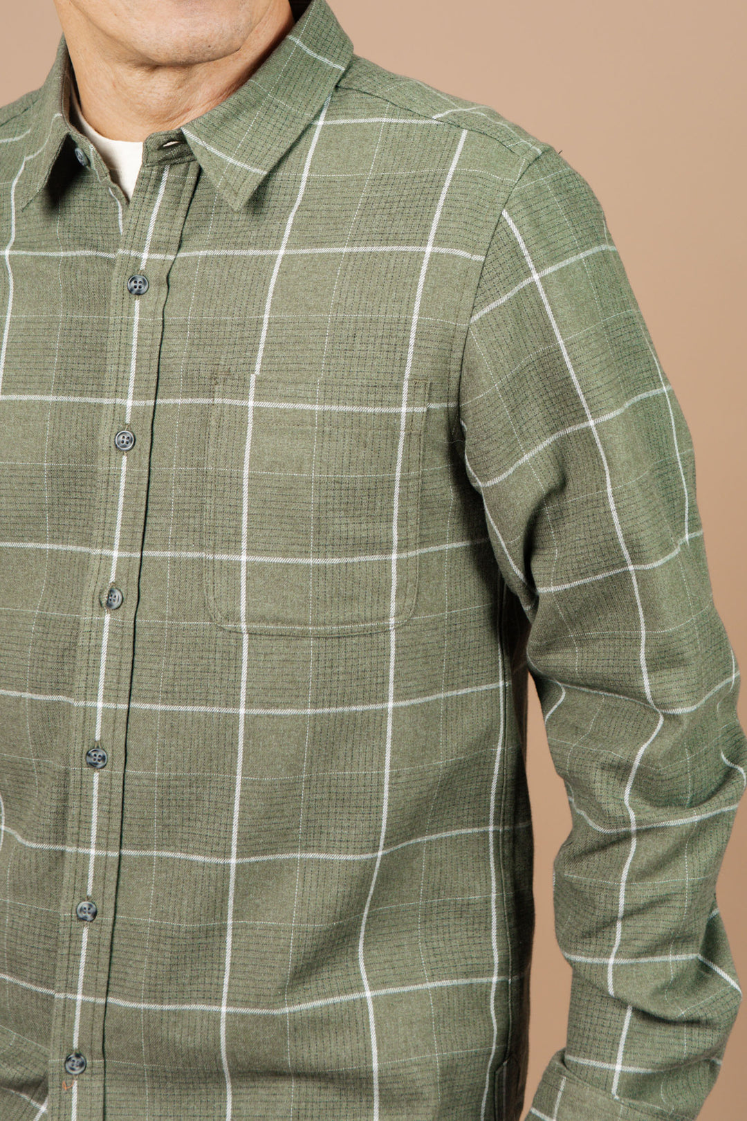 A person wears the Bridge & Burn Larson Shirt in Rosemary Twill Windowpane, shown from the chest up against a plain beige background.