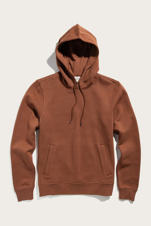 The Williams Pullover Hoodie in Burnt Umber by Bridge & Burn, made from organic cotton, features a front pouch pocket and drawstrings, shown laid flat on a light background.