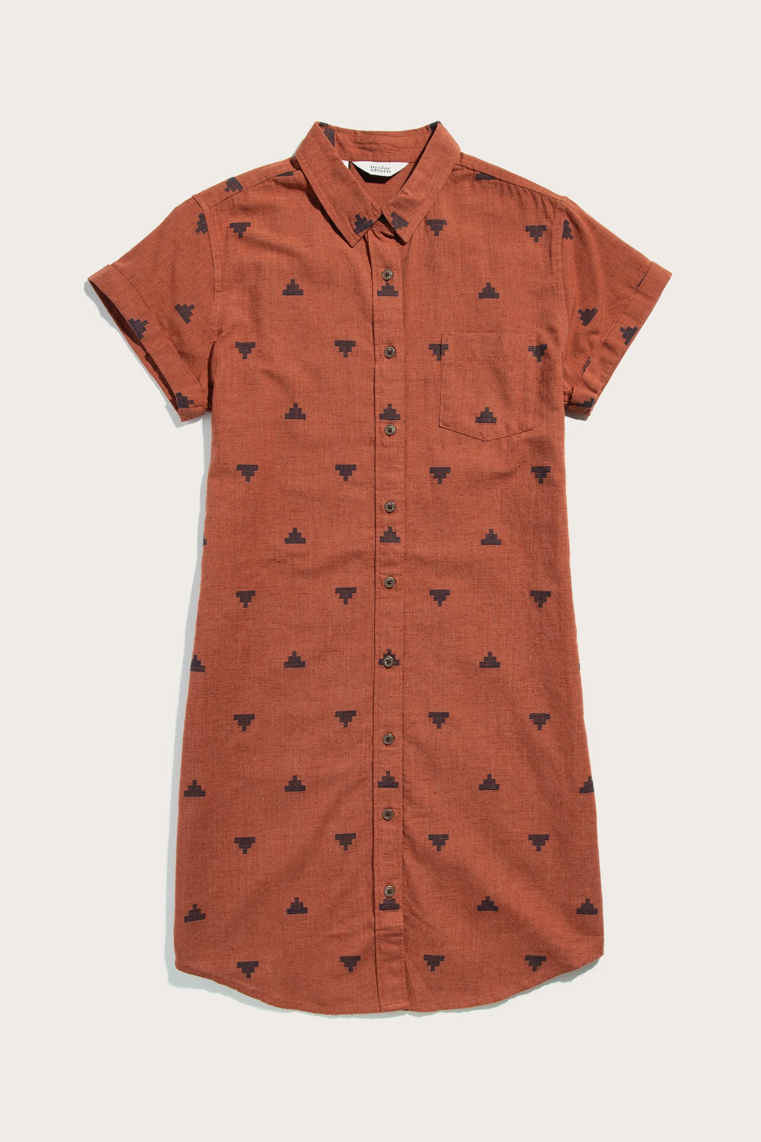The Loren Shirt Dress by Bridge & Burn features a rust color, short sleeves, button front, collar, chest pocket, and subtle black pyramid fil-coupé details throughout.