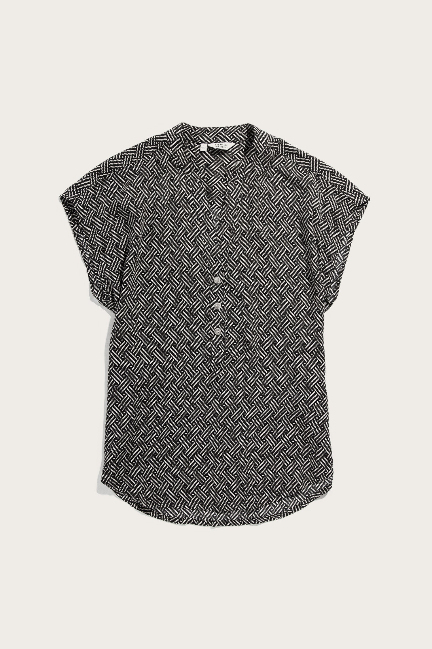 The Ladd Shirt by Bridge & Burn is a short-sleeve pullover blouse featuring a black and white geometric zigzag pattern, button-down front, and collar, shown laid flat on a light background.
