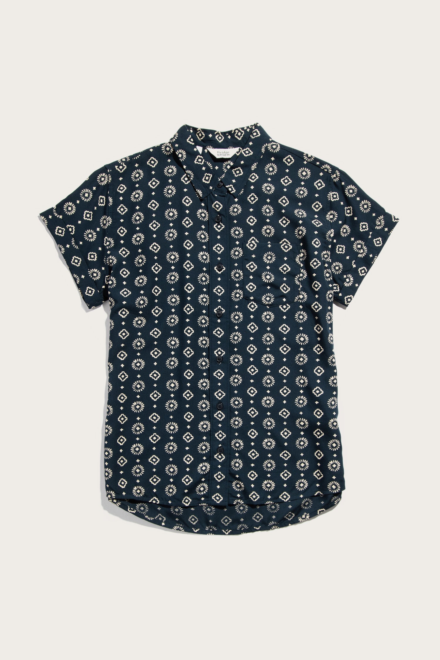 The Bridge & Burn Bea Shirt in Midnight Sundance is a tailored fit, short-sleeve button-down featuring a dark navy base with a white geometric diamond pattern, shown flat on a white surface for stylish and comfortable appeal.