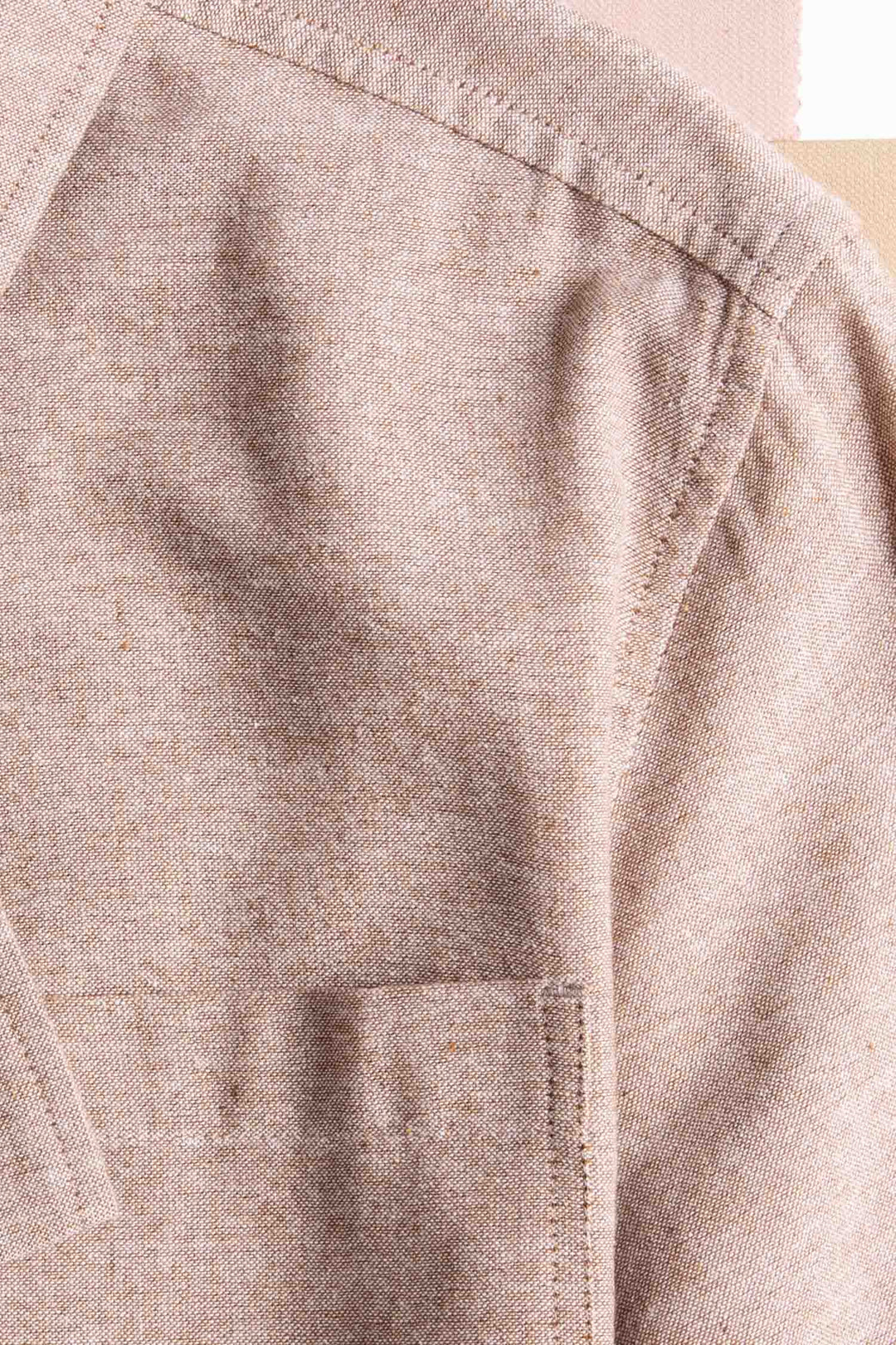 Close-up of the Bridge & Burn Bea Shirt in rust chambray, showcasing the shoulder, sleeve seam, pocket, and collar—sustainably crafted and set against a neutral background.