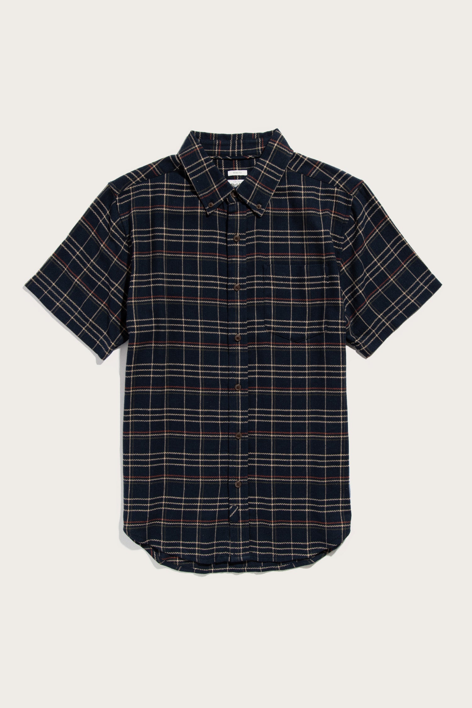 The Jordan Slim Shirt by Bridge & Burn features dusk herringbone plaid in black, tan, and white. Made from recycled cotton, it has short sleeves, a chest pocket, curved hem, and classic collar for versatile style.