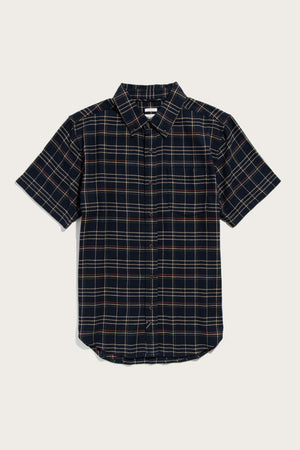 The Jordan Slim Shirt by Bridge & Burn features dusk herringbone plaid in black, tan, and white. Made from recycled cotton, it has short sleeves, a chest pocket, curved hem, and classic collar for versatile style.
