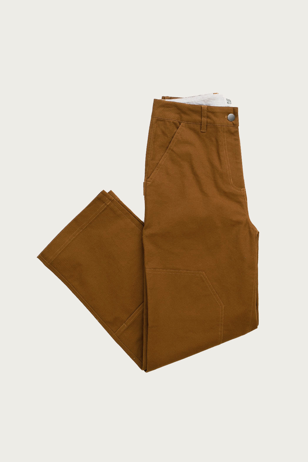 The Bowden Utility Pant in Hickory Canvas by Bridge & Burn features front pockets, belt loops, a button closure, and reinforced knees—shown neatly folded on a plain white background.