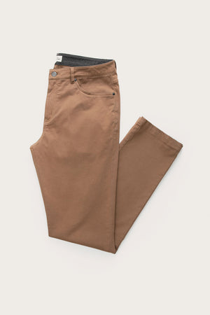 The Bridge & Burn Polk Pant in brown, a straight-fit design with 5-pocket styling, is neatly folded with one leg crossed over the other on a plain white background.