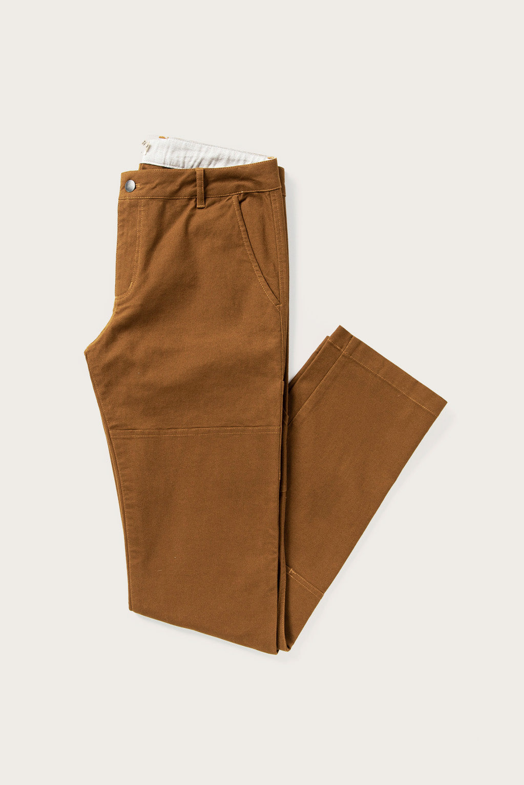 The Bridge & Burn Wallace Utility Pant in Hickory Canvas, featuring visible front pockets, a button waistband, and reinforced knees, is shown neatly folded on a light neutral background.