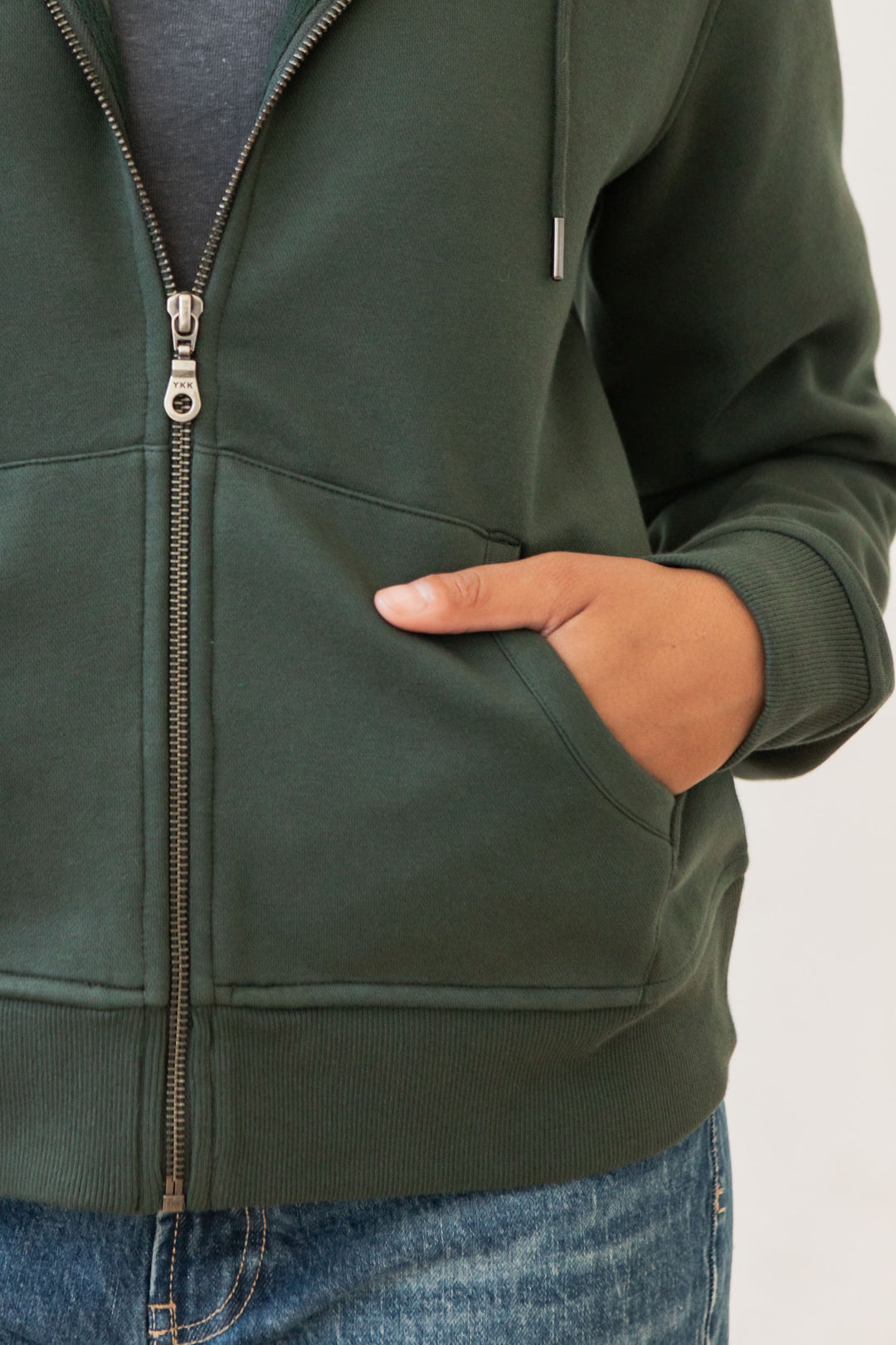 A person wearing the Bridge & Burn Mason Hoodie in Forest Night stands with one hand in the front pocket. The photo is cropped to show just the torso and part of the arm.