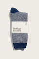 A pair of Bridge & Burn Helix Sock / Navy, featuring a blue and white pattern, recycled material, branded label, and round logo, displayed on a plain white background.