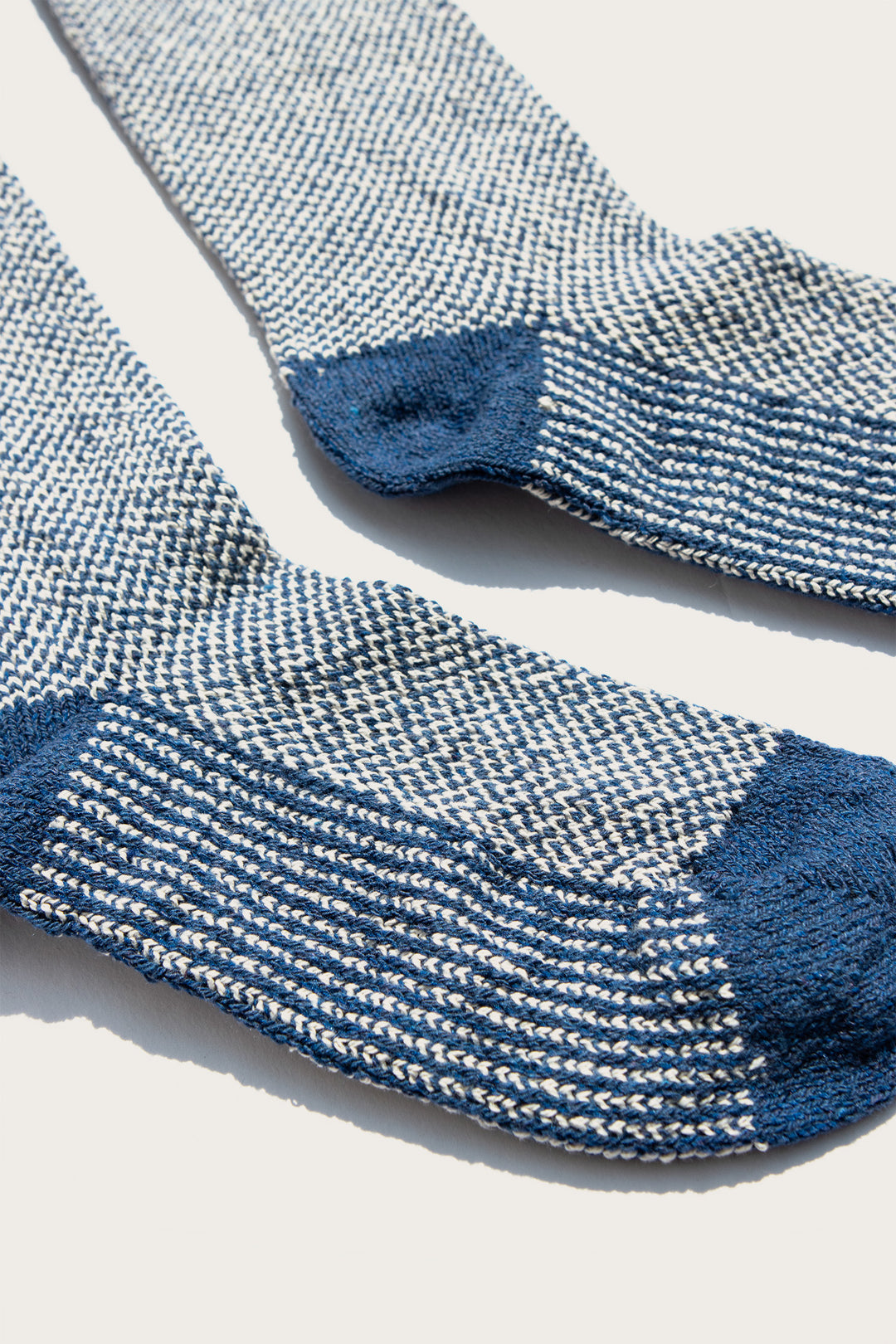 A close-up of the Bridge & Burn Helix Sock in Navy, featuring a white and blue speckled pattern with solid navy heels and toes, laid out flat on a light background.