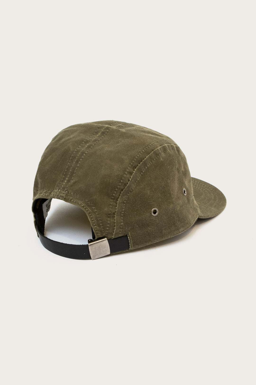 The Bridge & Burn Camper Waxed 5 Panel Cap in Moss is shown from the back, featuring a black adjustable strap with metal buckle and two metal eyelets for ventilation, against a plain off-white background.