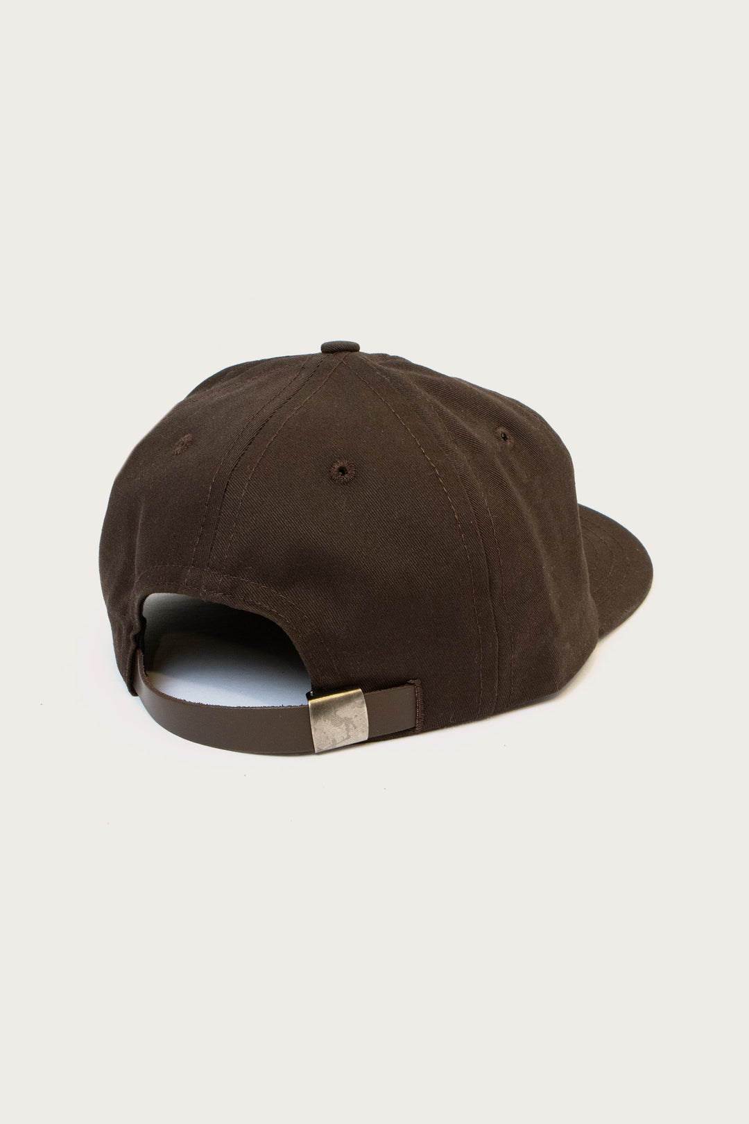 The Bridge & Burn Tree Cap in Espresso is shown from the back, highlighting its dark brown cotton twill, adjustable leather strap, and metal clasp against a plain light background.