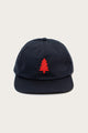 The Bridge & Burn Tree Cap in navy is a cotton twill hat featuring a red embroidered pine tree on the front and a leather size-adjustment strap, shown against a plain light background.