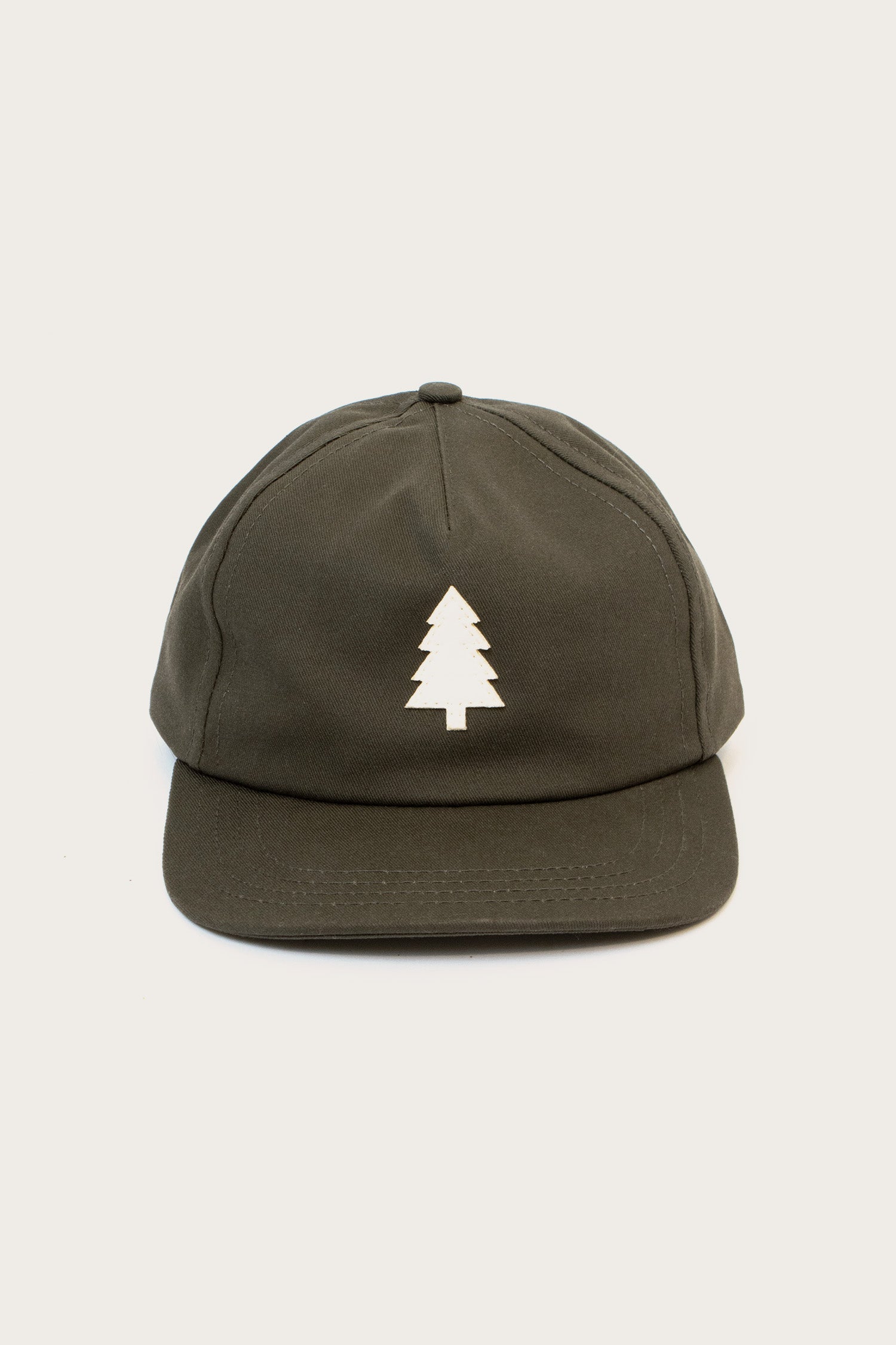 The Tree Cap / Olivewood by Bridge & Burn is a dark green pinch front hat with a white custom tree appliqué on the front, shown against a plain light background.