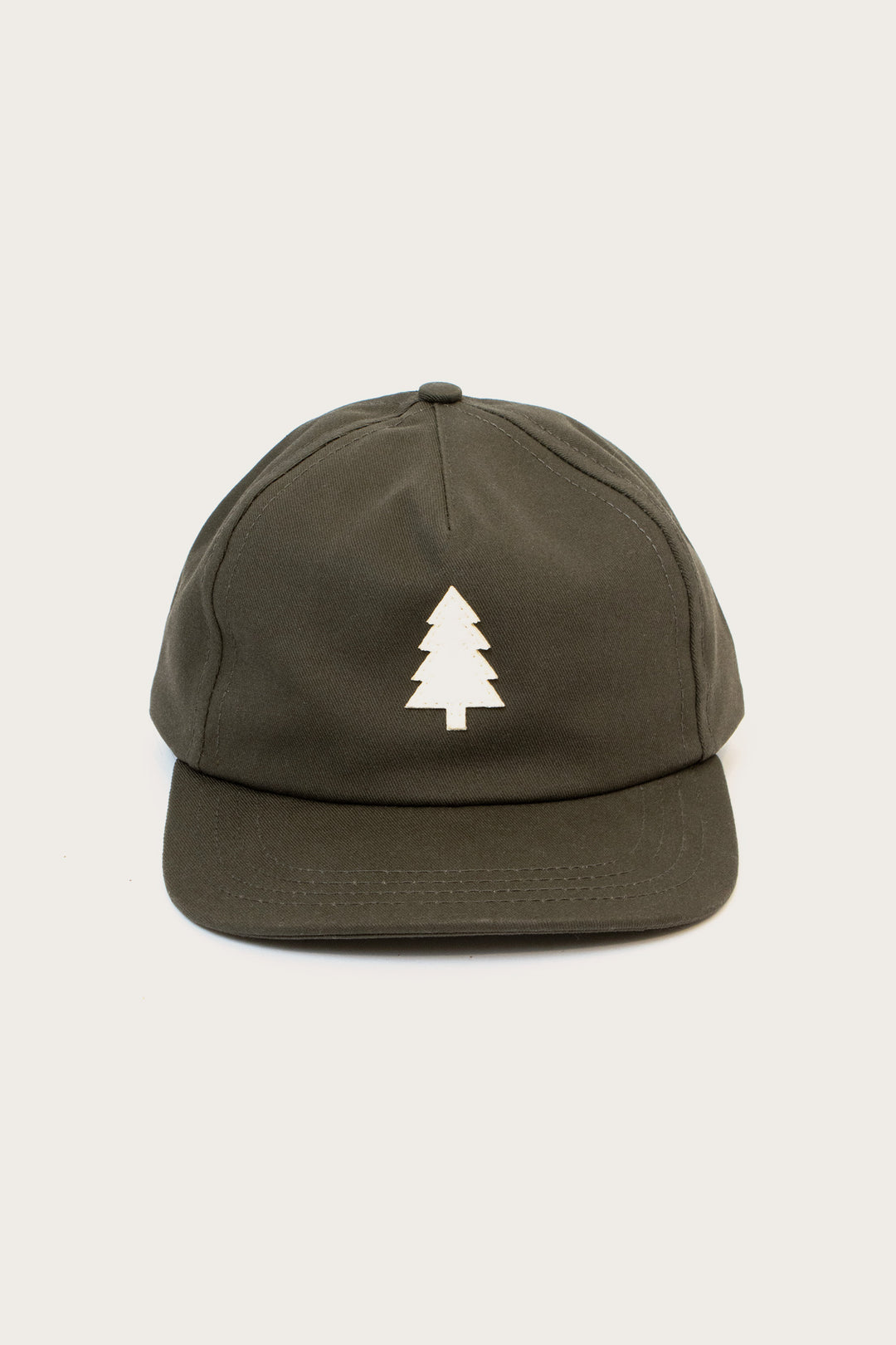The Tree Cap / Olivewood by Bridge & Burn is a dark green pinch front hat with a white custom tree appliqué on the front, shown against a plain light background.
