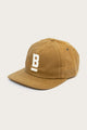 The Bridge & Burn B Flat Waxed Cap in brown is made from British Millerain waxed canvas, features a curved brim and bold white 