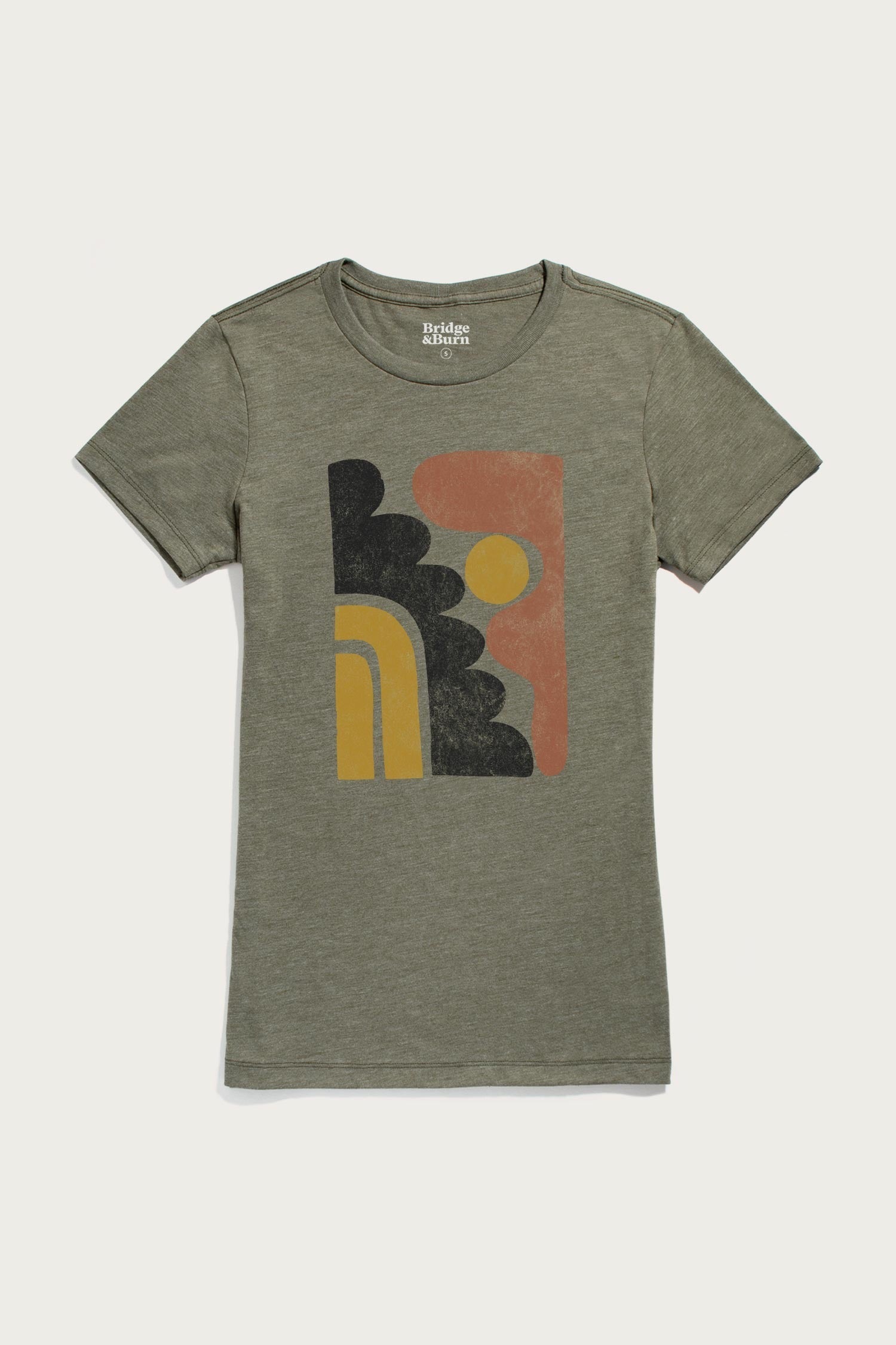 The Bridge & Burn Women's Ladera Tee in olive is a lightweight organic cotton shirt featuring a retro graphic with black arches, a yellow semi-circle, and an orange sun on the front.