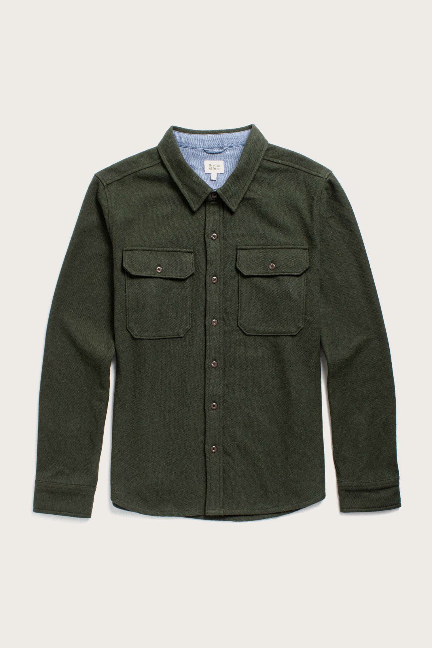 The Bridge & Burn Pointer Overshirt in Dark Sage is a long-sleeve, button-up twill shirt with two chest pockets and a collar, made from recycled fibers and shown against a plain light background.