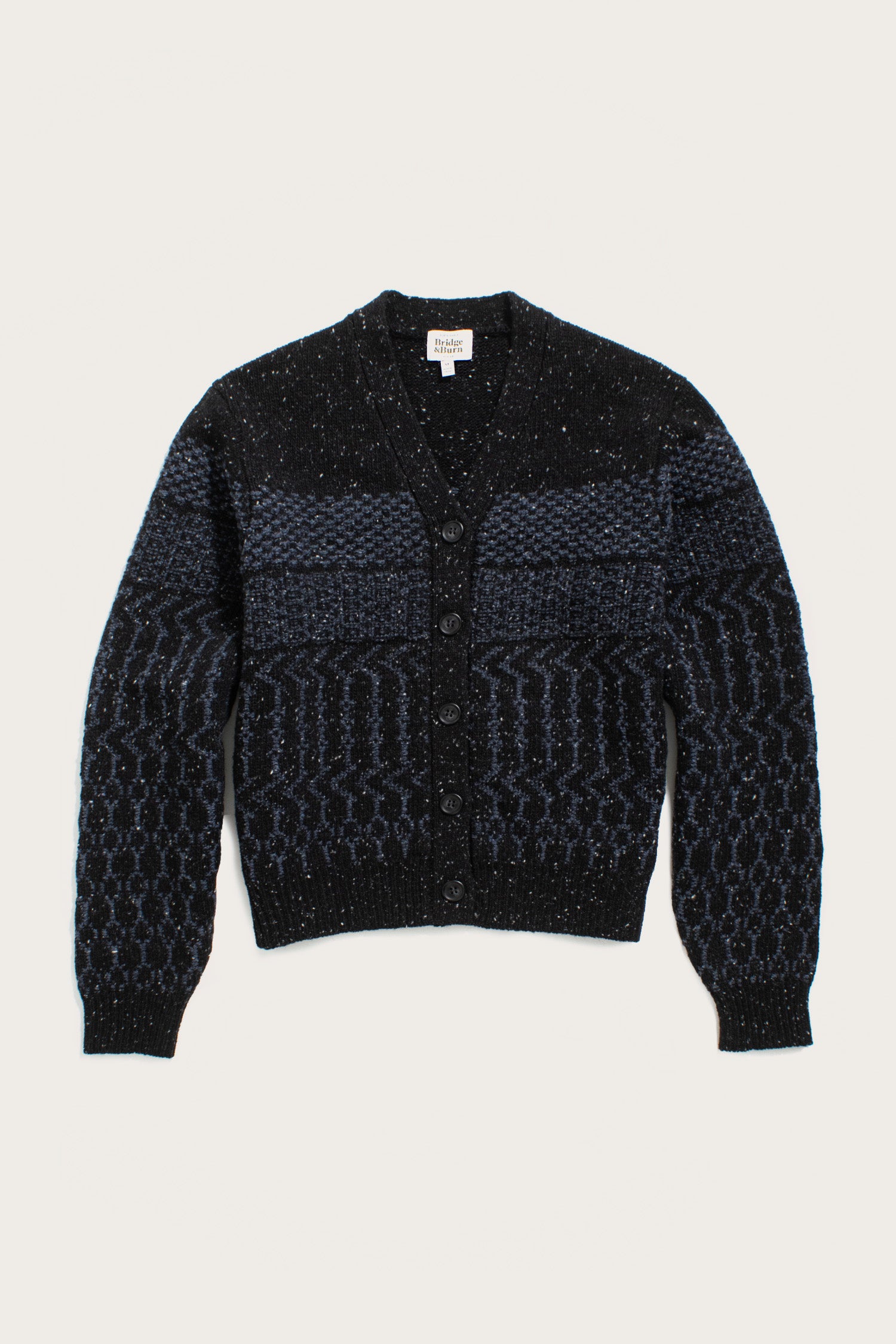 The Bridge & Burn Juneau Cardigan in Midnight Tweed is an artisan-inspired dark blue and black knit with textured patterns, button front, and ribbed cuffs and hem, shown on a plain white background.