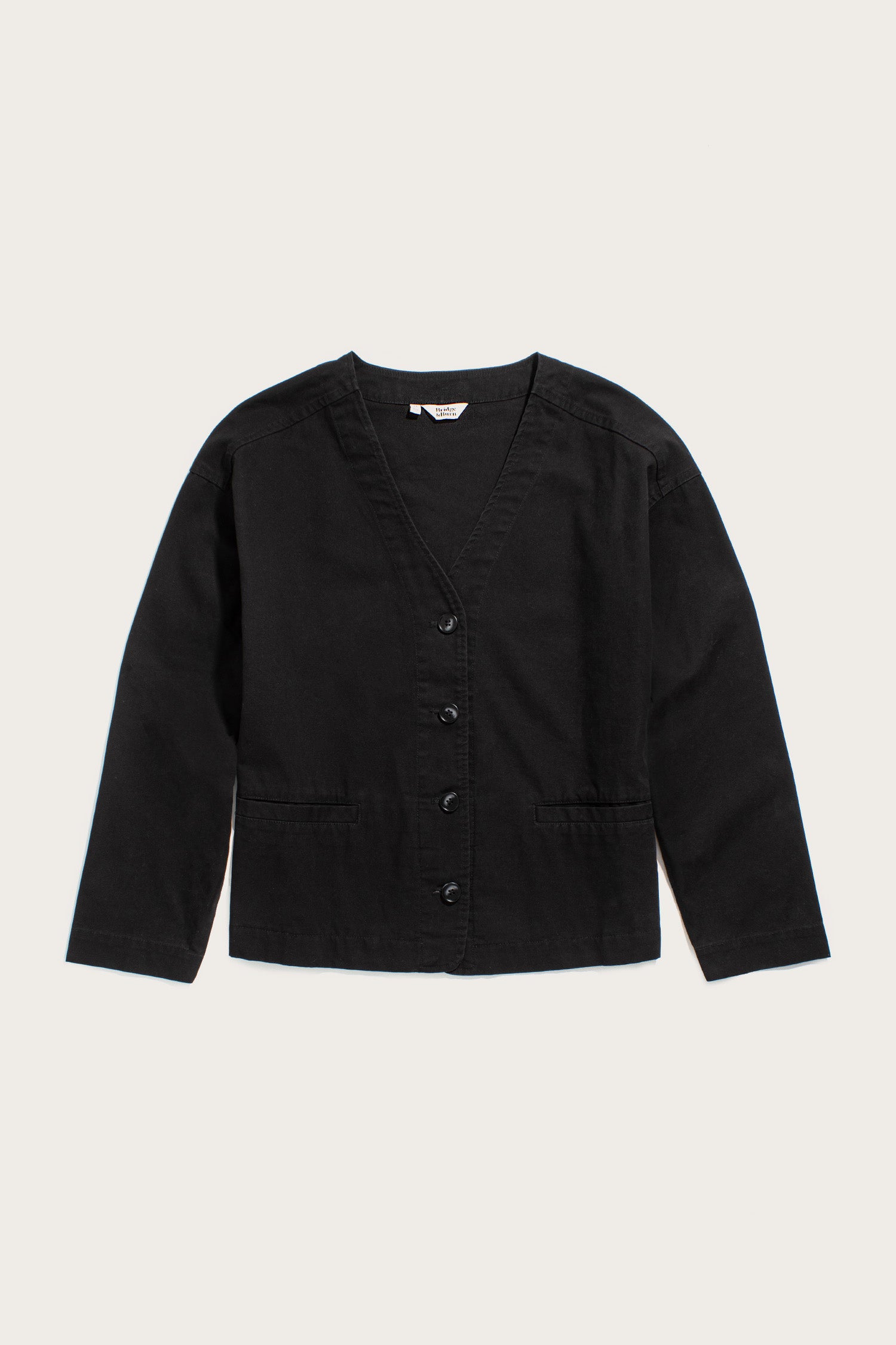 The Bridge & Burn Lee Jacket in black canvas features a modern boxy fit, V-neckline, button-down front, and two front pockets, shown laid flat on a light background.