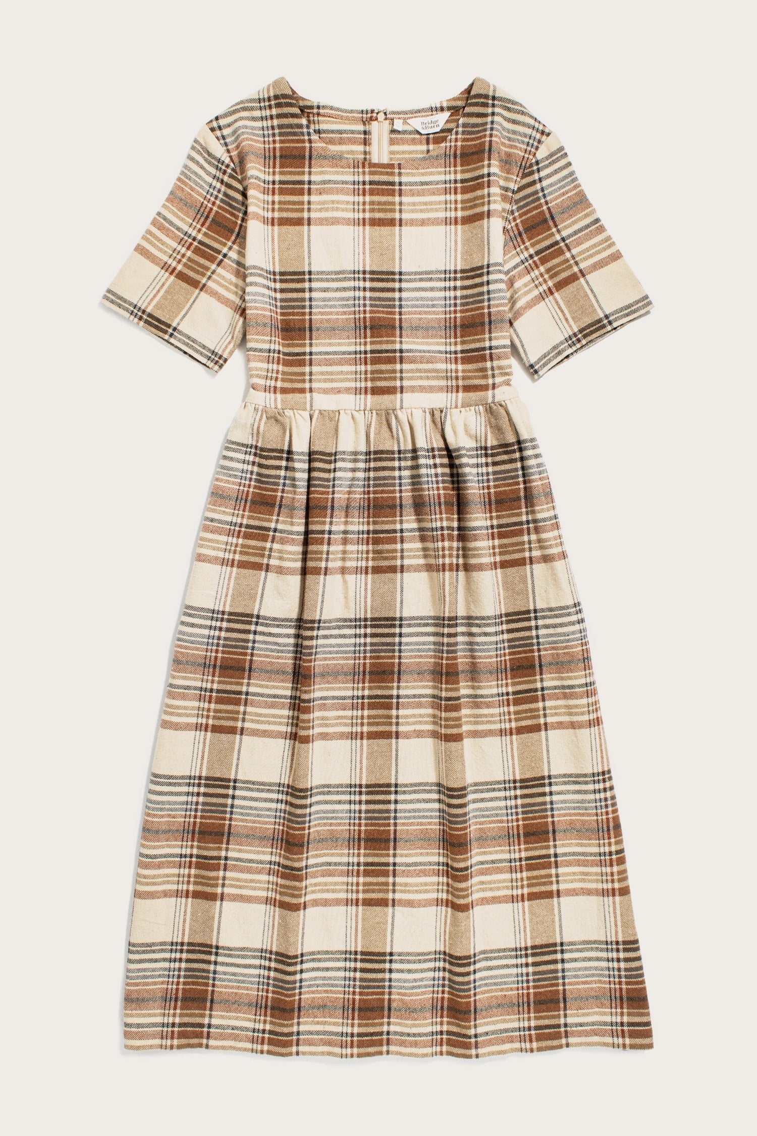 The Perry Dress / Latte Plaid by Bridge & Burn is a midi-length silhouette with short sleeves, a fitted waist, and a brown, beige, and black plaid on cream recycled cotton. A gathered skirt adds fullness for easy charm.